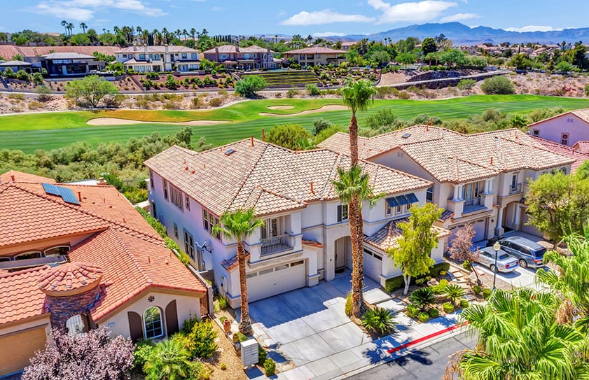 Vegas-home-on-golf-course-from-air Drone photo of a home for sale with views of a golf course and Las Vegas mountains